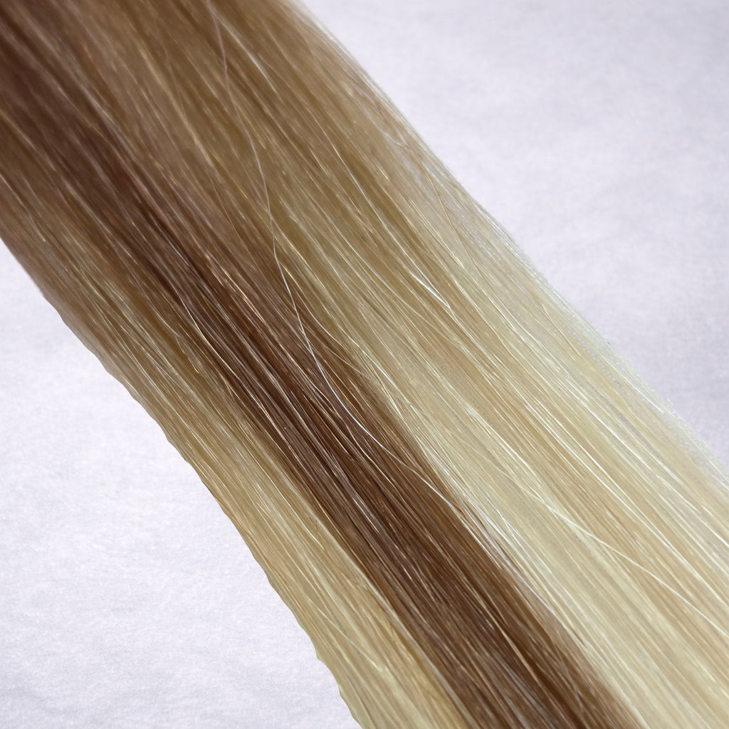 Studio Collection shade swatch in Bronzed Cashmere #T10P10/24/60, featuring a dimensional blend of soft petal blonde, cashmere blonde, and creamy vanilla blonde tones with bronzed ribboned highlights, a silky finish, and natural shine.

