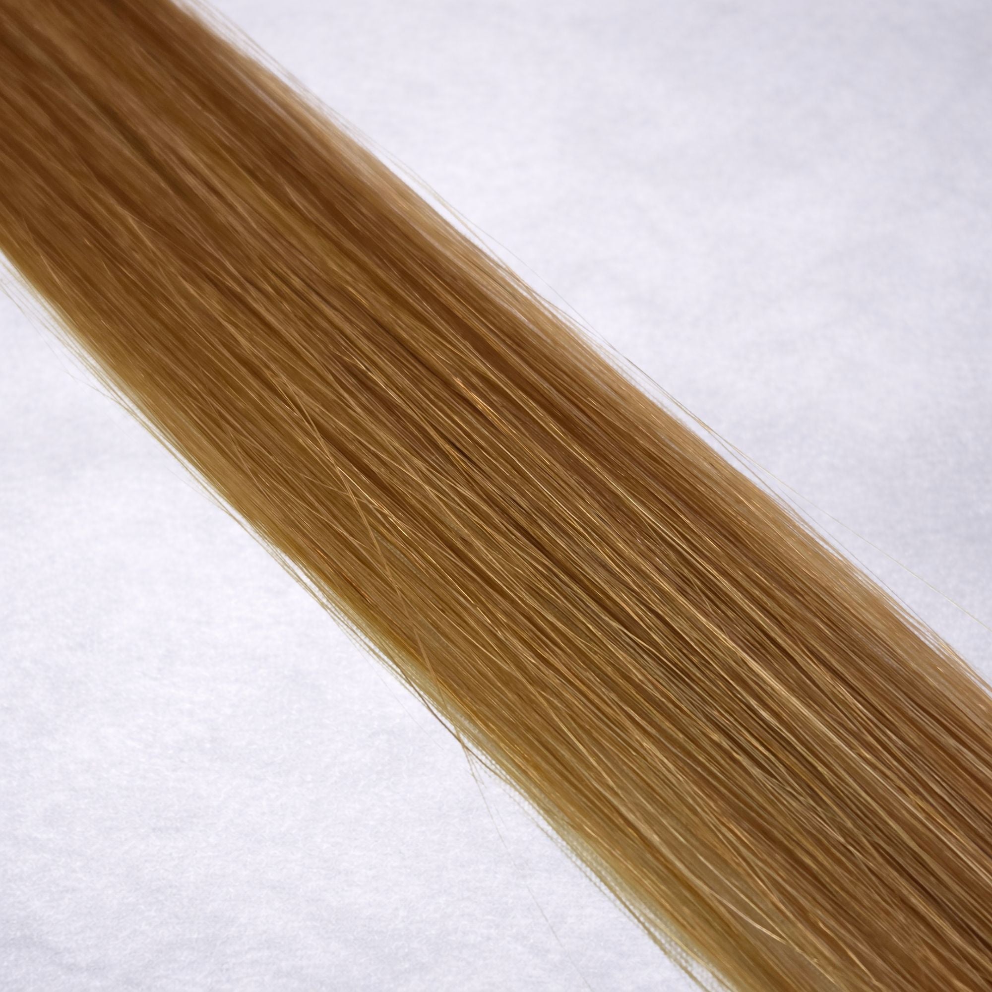Luxury Remy human hair extension shade swatch in Butternut #8 from the Remalisse Studio Collection, featuring a warm dark blonde tone with golden caramel undertones, soft dimension, a silky finish, and natural shine.