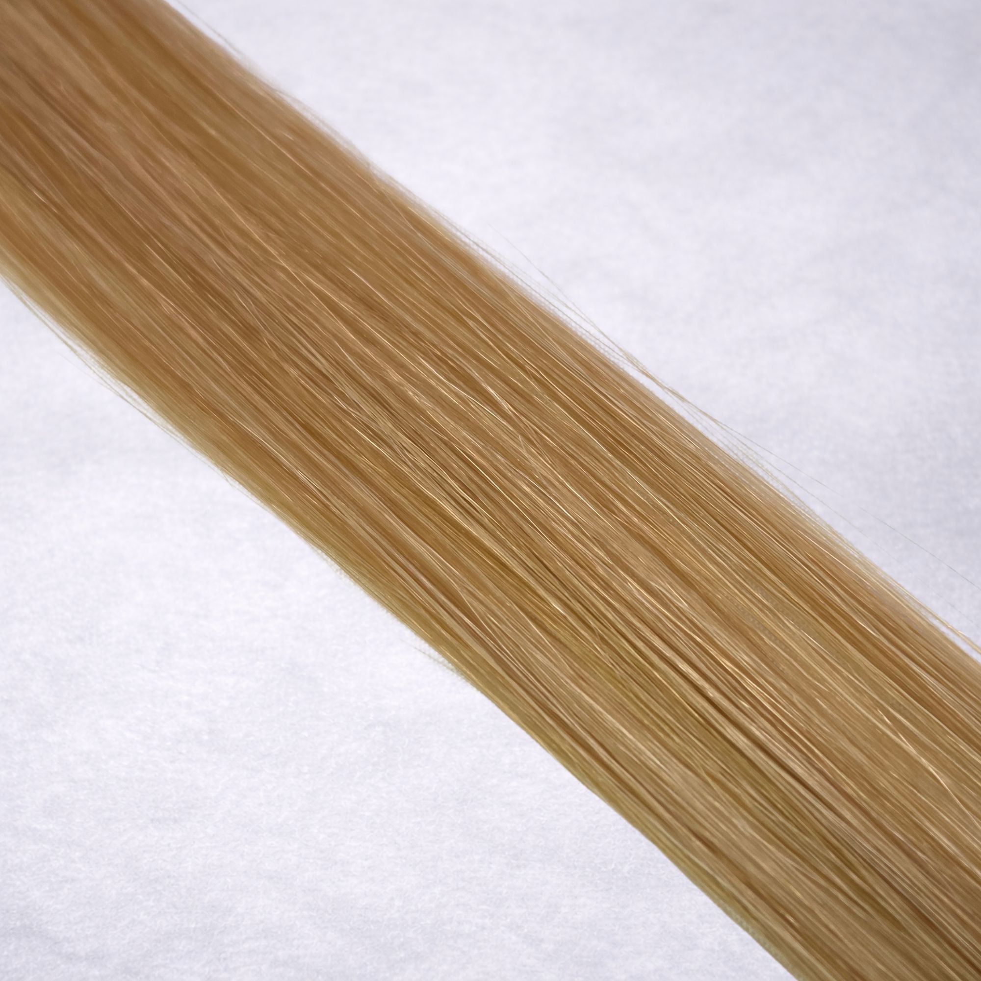 Luxury Remy human hair extension shade swatch in Butterscotch #14 from the Remalisse Studio Collection, featuring a warm golden blonde tone with rich caramel undertones, soft dimension, a silky finish, and natural shine.