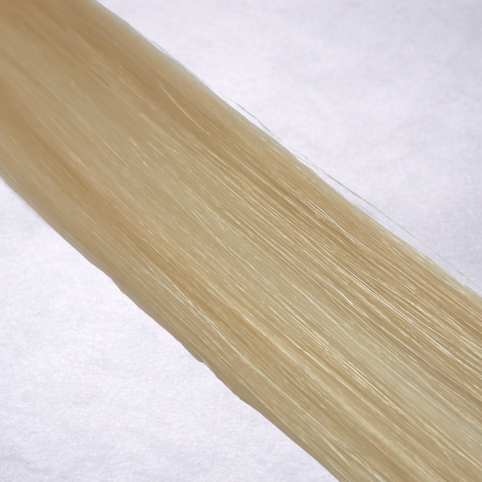 Luxury Remy human hair extension shade swatch in Creamy Blonde #613 from the Remalisse Studio Collection, featuring a warm light blonde tone with creamy golden undertones, soft dimension, a silky finish, and natural shine.