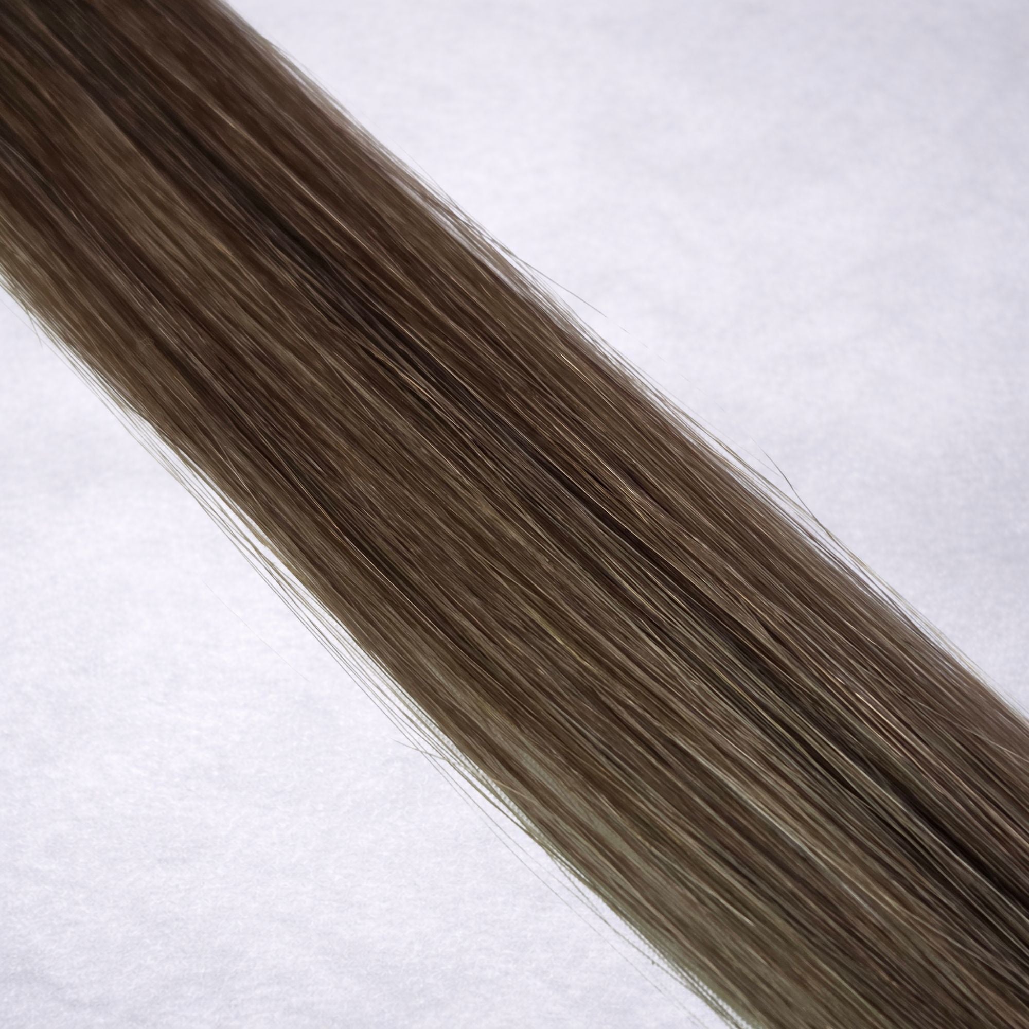 Luxury Remy human hair extension shade swatch in Hazelnut Ash #7, featuring a muted medium brown tone with cool ash undertones, soft dimension, a silky finish, and natural shine.