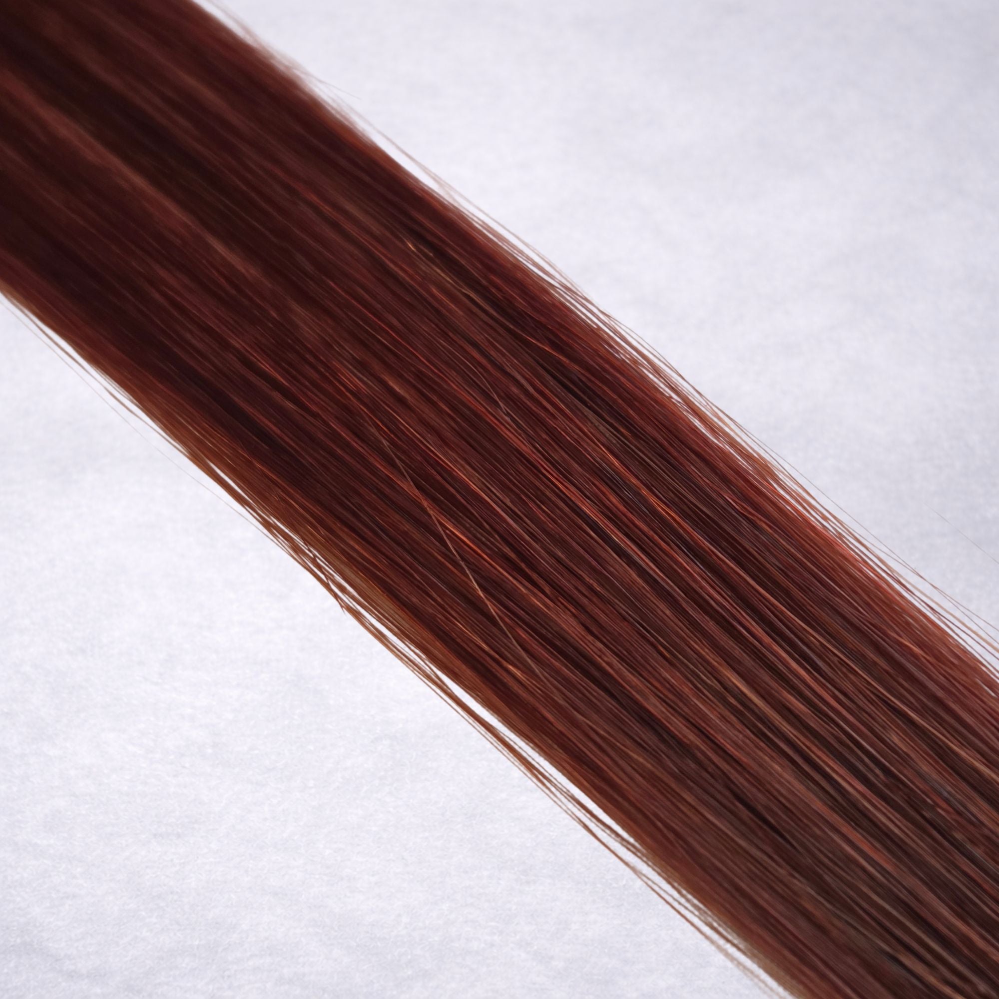 Luxury Remy human hair extension shade swatch in Mulberry #34 from the Remalisse Studio Collection, featuring a rich deep red tone with warm auburn undertones, soft dimension, a silky finish, and natural shine.