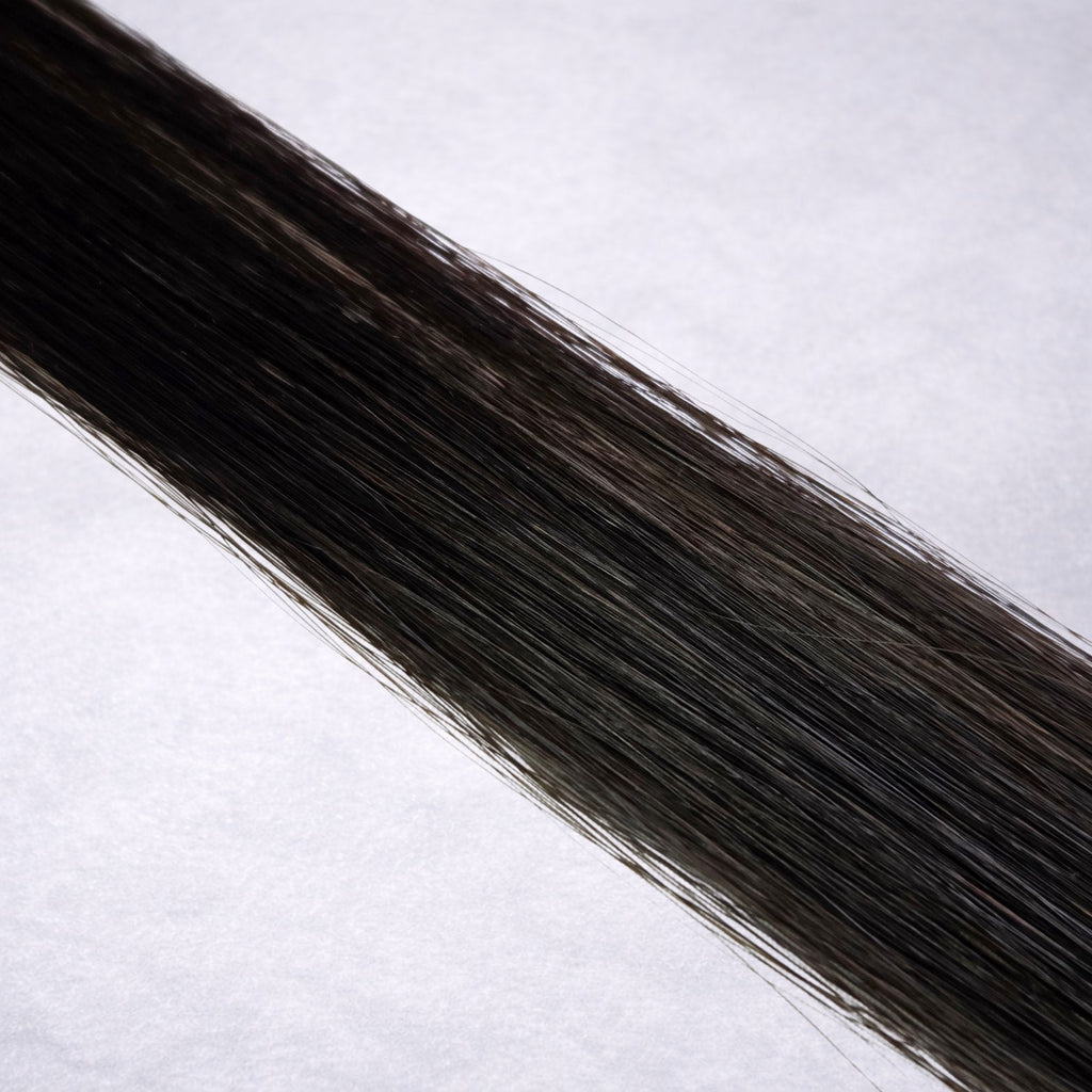 Luxury Remy human hair extension shade swatch in Raven #1B, featuring a soft natural black tone with subtle warm depth, a silky finish, and natural shine.