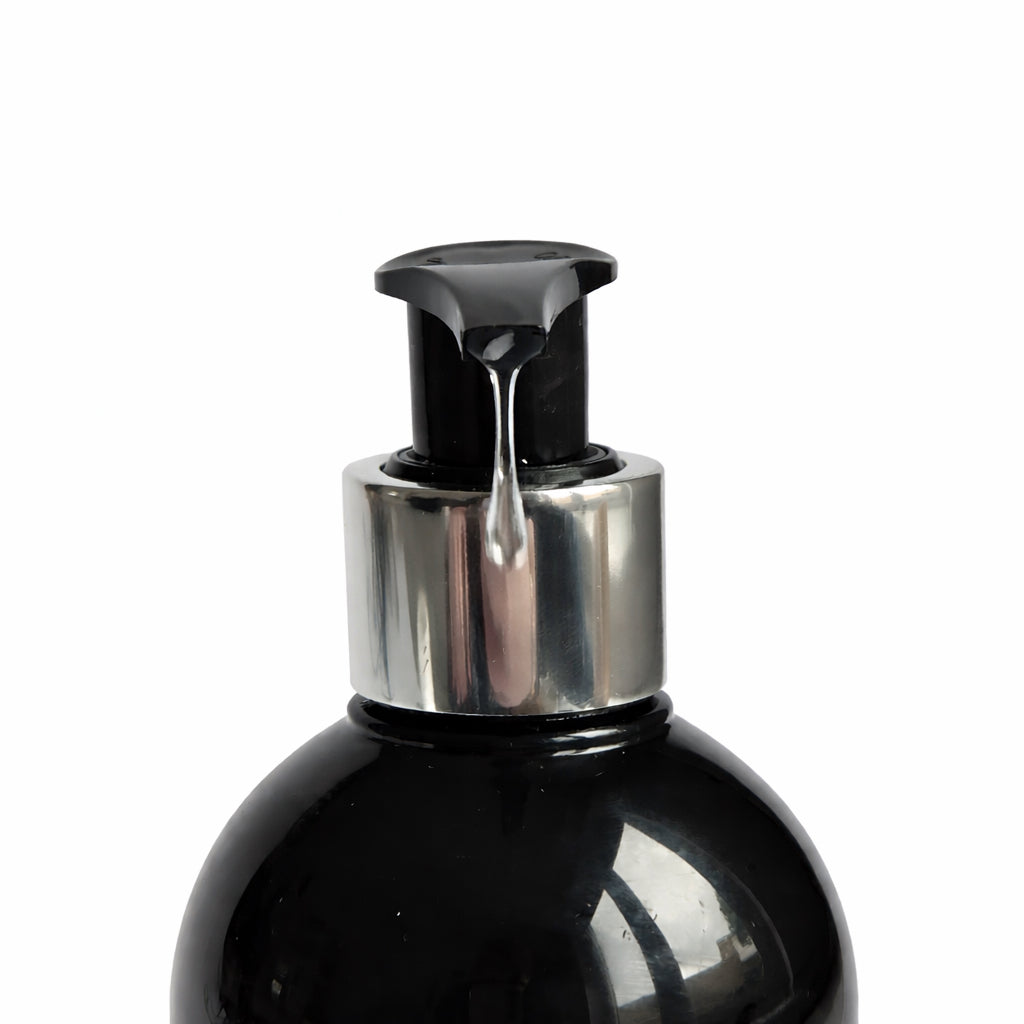 close up of Remalisse pump shampoo dispenser releasing product from a black bottle with silver collar. 