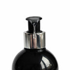 close up of Remalisse pump shampoo dispenser releasing product from a black bottle with silver collar. 