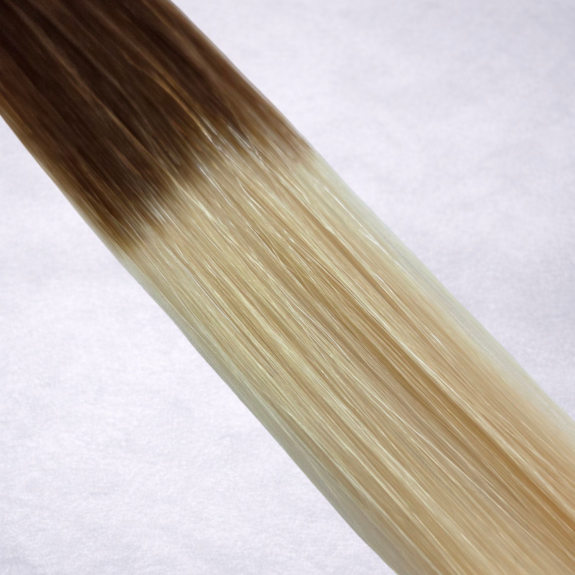 Studio Collection shade swatch in Rooted Vanilla #T4/60, featuring a dimensional blend of rich chocolate brown roots melting into creamy vanilla blonde lengths, with a silky finish and natural shine.