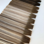 Close up of Remalisse Studio Flat Weft hair extensions in multiple brunette and blonde shades displayed on a white background, showing the seamless flat weft edge and colour variation.