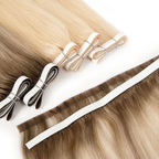 Close-up of blonde and brunette invisible tape weft hair extensions displayed alongside matching tape sections. The Remy human hair features soft blended tones with ultra-flat adhesive tape wefts designed for a seamless, scalp-like finish against a clean white background.