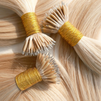 Close-up of blonde nano tip hair extensions arranged in bundles, featuring ultra-small nano tip attachments and silky Remy human hair. The lightweight strand-by-strand extensions showcase smooth texture, glossy shine and discreet nano tip construction against a clean light background.