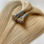 Blonde nano tip hair extensions laid out in a smooth fan shape with ultra-small strand tips visible at the top. The silky Remy human hair features a glossy finish and lightweight strand-by-strand nano tip construction against a clean light background.