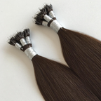 Close-up of dark brunette nano tip hair extensions bundled together, featuring ultra-small metal nano tip attachments and smooth silky Remy human hair. The strand-by-strand extensions showcase a sleek, glossy finish against a clean white background.