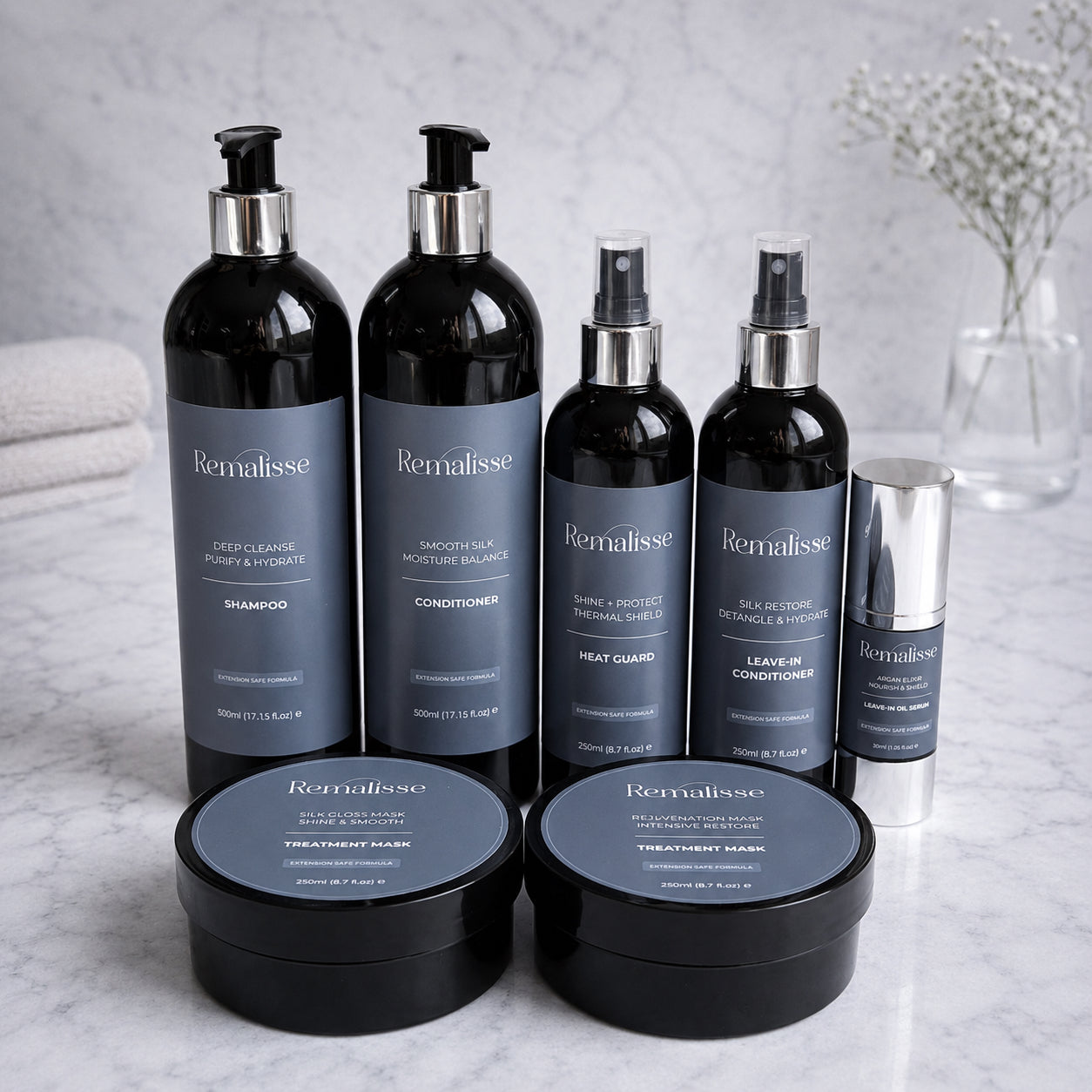 Remalisse professional hair extension aftercare collection including shampoo, conditioner, treatment masks, protein spray, silk restore leave-in conditioner, heat protection and argan oil serum displayed on marble background. 