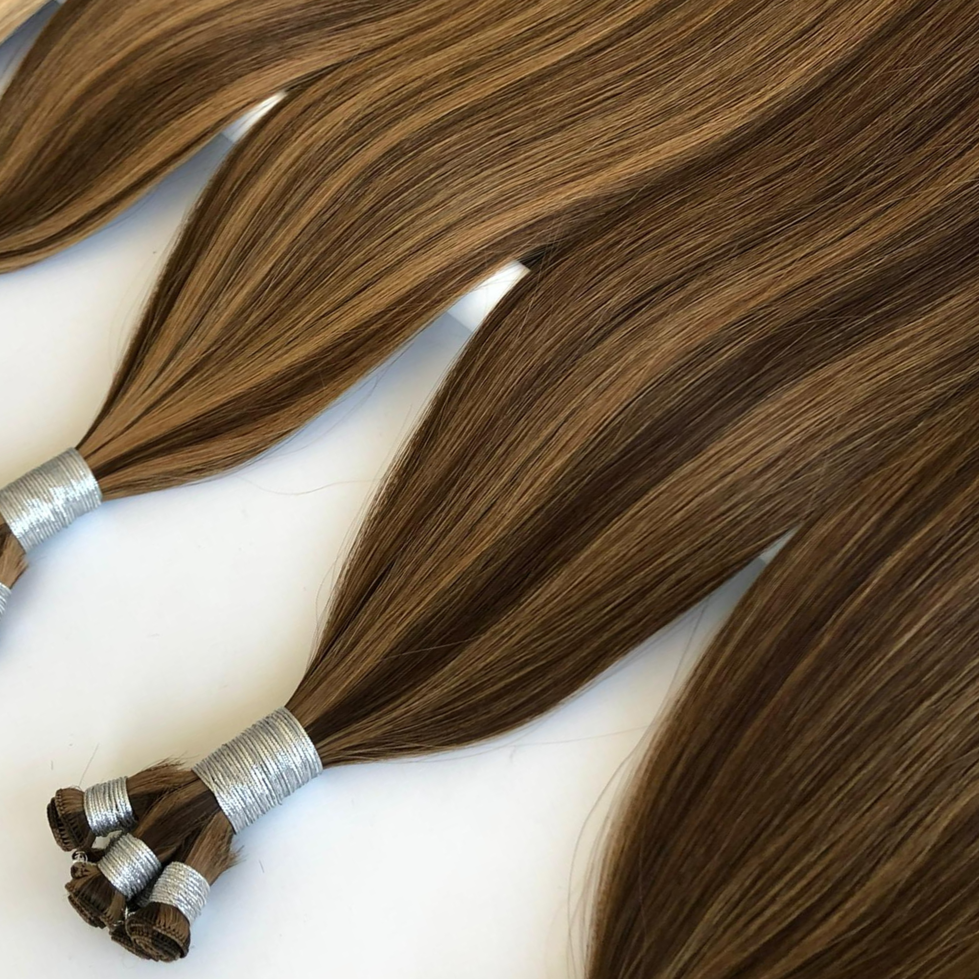 Studio hand-tied weft hair extensions in brown balayage shade on white background