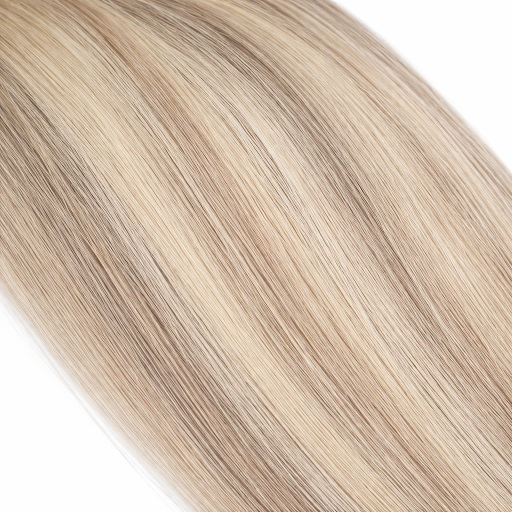 close-up of straight blonde hair extensions showing smooth silky texture and natural blended tones on a plain white background.