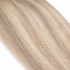 close-up of straight blonde hair extensions showing smooth silky texture and natural blended tones on a plain white background.