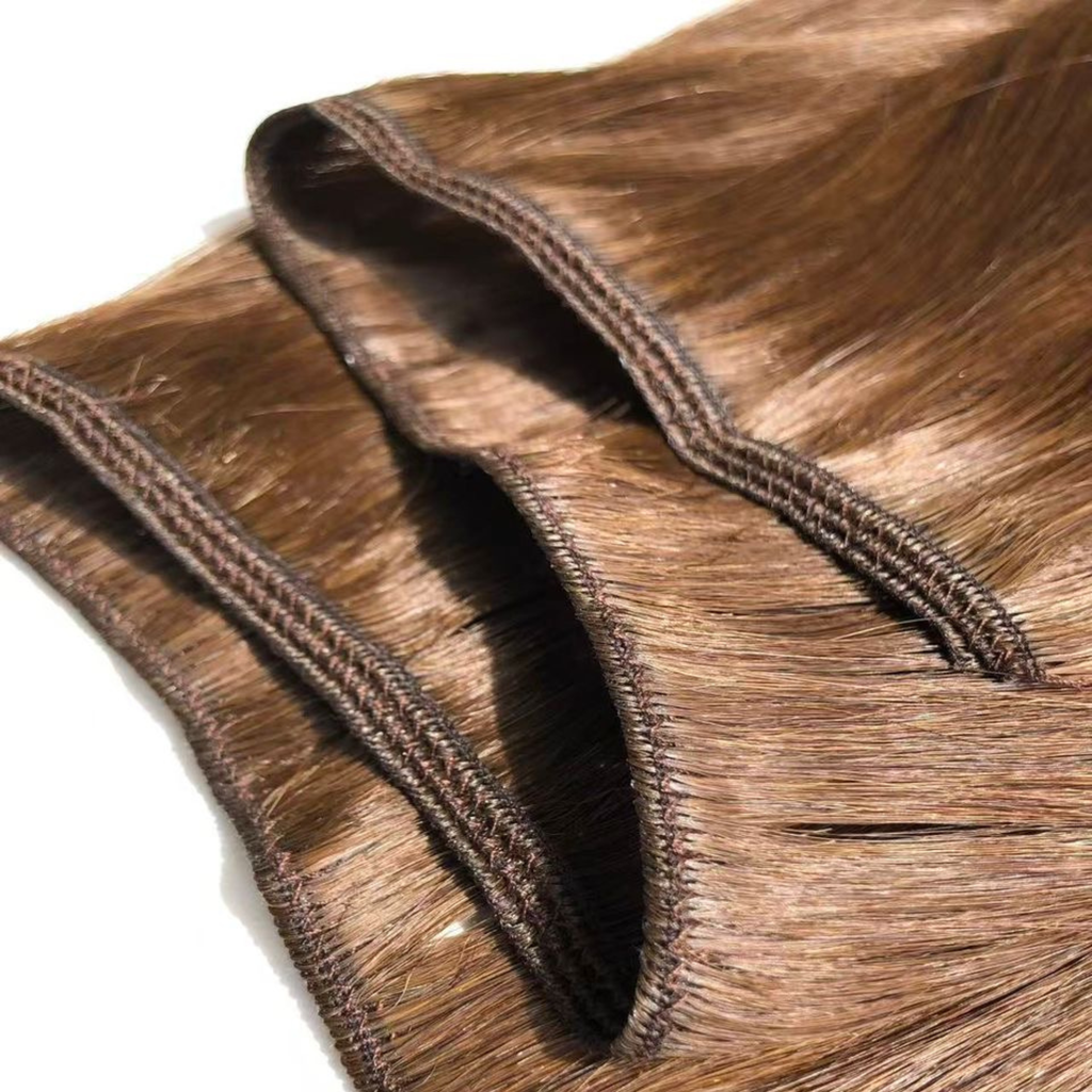 Close-up of multiple Remalisse volume weft hair extensions layered over one another, showing the stitched weft construction, flexible seams and smooth brunette hair texture with a natural shine