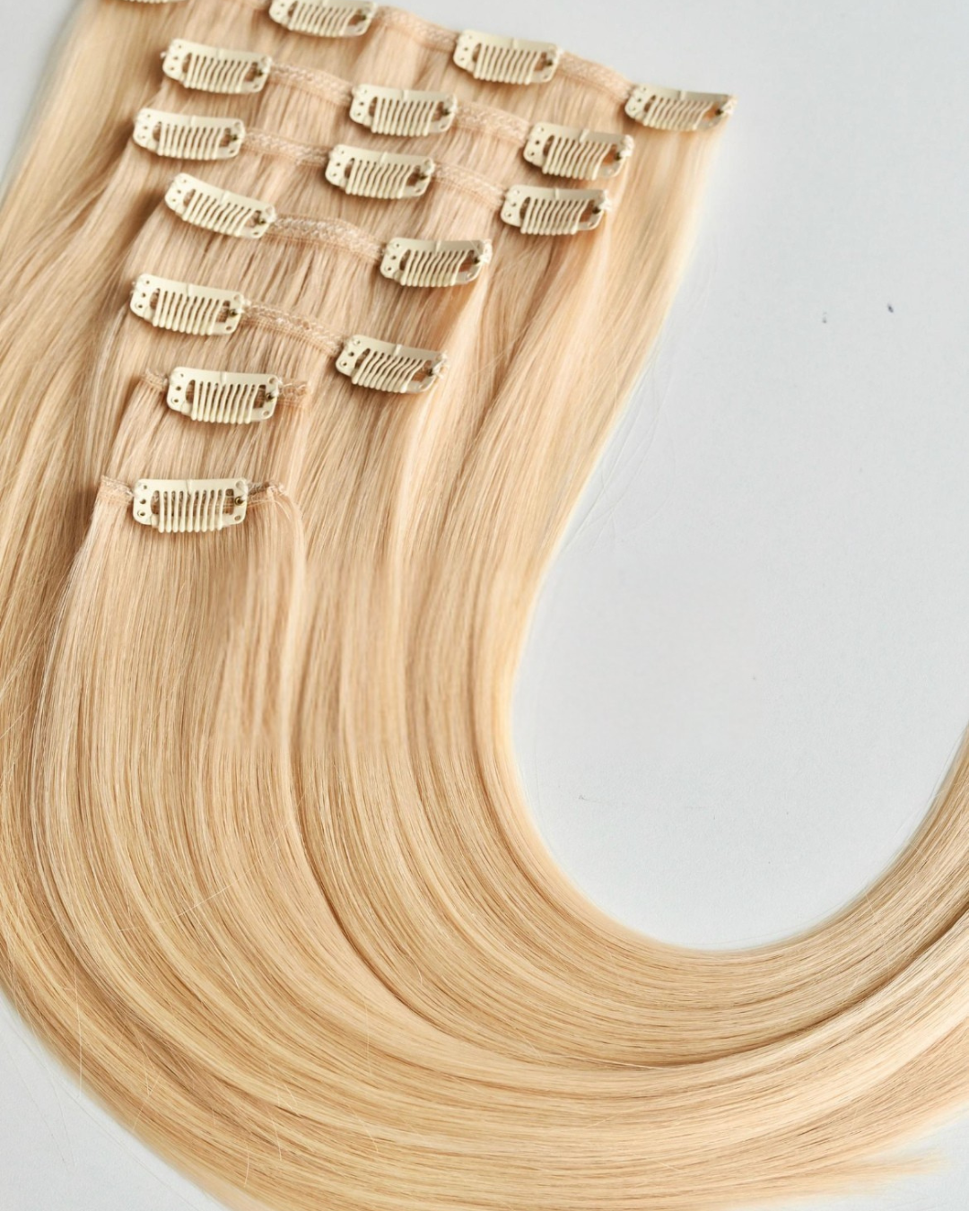 Studio Collection Remy human hair clip-in extensions in icy blonde shades, featuring seamless multi-piece clip wefts with lightweight discreet construction, silky smooth texture and natural salon-quality shine.